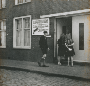 876762 Afbeelding van drie jongelui bij de ingang van het klooster Genazzano van de Zusters Augustinessen van ...